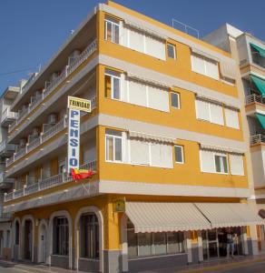 un edificio amarillo con un letrero que lee hotel en Pensión Trinidad, en Guardamar del Segura