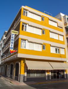 un edificio amarillo en la esquina de una calle en Pensión Trinidad, en Guardamar del Segura