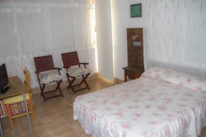 a bedroom with a bed and two chairs and a table at Pensión Trinidad in Guardamar del Segura