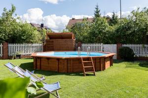 a hot tub in a yard with two lawn chairs at Bałtyk Resort in Rewal