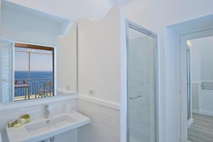 La salle de bains blanche est pourvue d'un lavabo et d'un miroir. dans l'établissement Il Corallo, à Praiano