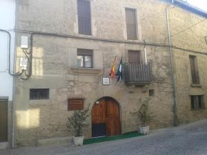 un edificio de piedra con puerta de madera y balcón en Casa Rural Corvina, en Acebo