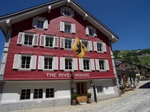 ein rotes Gebäude mit dem Flusshaus darauf in der Unterkunft Boutique Hotel The River House in Andermatt