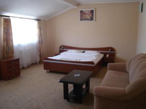 um quarto com uma cama, um sofá e uma cadeira em Izumrud em Uzhhorod