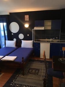 a small room with a blue bed and a kitchen at Apartmani Berghaus in Zlatibor