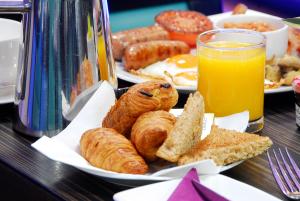 un plato de desayuno con bollería y un vaso de zumo de naranja en Park Grand Marble Arch, en Londres