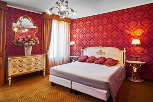 a bedroom with a bed with red walls and a mirror at Hotel Gardena in Venice
