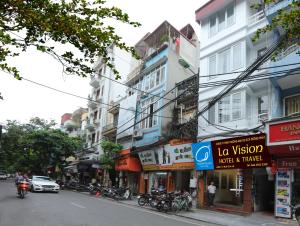 una concurrida calle de la ciudad con muchos edificios y motos en Hanoi La Vision Hotel, en Hanói