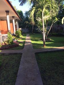 a walkway in front of a house with palm trees at Amed Kunara Guest House in Amed