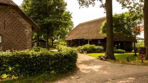 a brick house with a thatched roof and a sidewalk at Erfgoed & Logies Den Heijkant in Moergestel