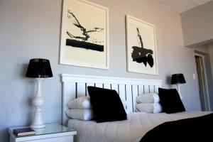 a bedroom with a white bed with two black pillows at Casa Do Mar Guest House in Praia do Tofo +44 photos