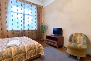 Schlafzimmer mit einem Bett, einem TV und einem Stuhl in der Unterkunft Home Hotel Apartments on Lva Tolstogo in Kiew