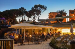 a group of people sitting at tables with umbrellas at 3HB Falésia Garden in Albufeira