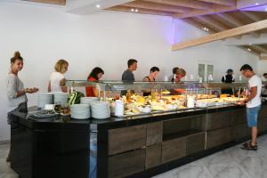 a group of people standing around a buffet with food at Saint George Palace in Perlopsimades