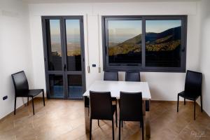 a dining room with a table and chairs and windows at Su AlevraXi in Villagrande Strisaili