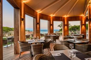 een restaurant met tafels en stoelen en de oceaan op de achtergrond bij 3HB Falésia Mar in Albufeira