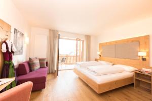 um quarto de hotel com duas camas e uma cadeira roxa em Panorama Hotel Flora em Villandro