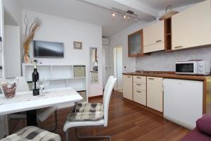 a kitchen with white cabinets and a table with a microwave at Apartments Tanja in Rovinj