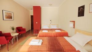 a hotel room with two beds and red chairs at Vila Dunavski Raj in Golubac