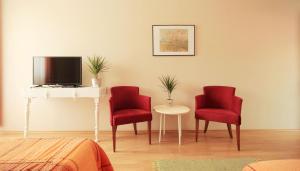 a room with two red chairs and a table and a tv at Vila Dunavski Raj in Golubac