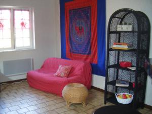 a living room with a pink chair and a shelf at Les Lutins in Sainte-Ruffine
