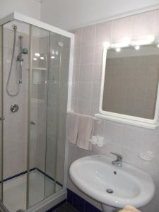 uma casa de banho com um lavatório e um chuveiro com um espelho. em Hotel Maremonti em Vico del Gargano