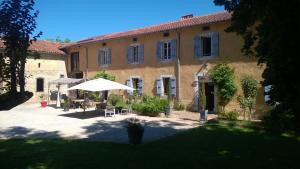 a building with an umbrella and a patio at Le Clos Galan in Galan