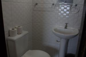 a white bathroom with a toilet and a sink at Pousada Betel - Moradas Familia Betel in Salvador