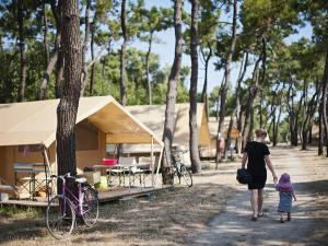 un homme et un enfant se promènent devant une tente dans l'établissement Huttopia Noirmoutier, à Noirmoutier-en-l'lle