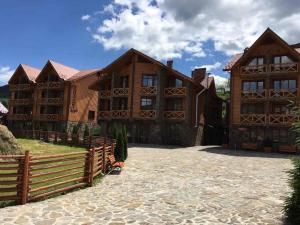 a large wooden house with a fence in front of it at Karpatski Zori Hotel in Bukovel