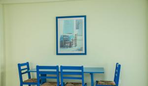 Paphinia SeaView Apartments في بافوس: طاولة وكراسي زرقاء مع صورة على الحائط
