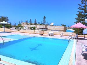 a large swimming pool with chairs and umbrellas at Virginia Beach Standalone Villa in El Alamein +19 photos