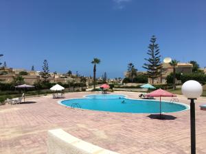 a swimming pool with umbrellas and tables and chairs at Virginia Beach Standalone Villa in El Alamein