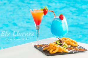 a drink and a plate of food next to a pool at Apartaments Els Llorers in Lloret de Mar