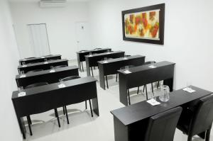 una habitación con mesas y sillas negras y una pintura en Ixnuk Class, en Piura