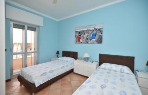 een blauwe slaapkamer met 2 bedden en een raam bij Appartamento Via Salento Gallipoli in Gallipoli