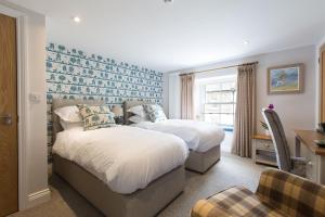 a bedroom with two beds and a desk and a chair at Bertram's in Warkworth