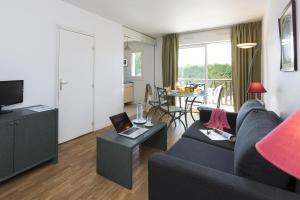 a living room with a couch and a table at Résidence Goélia Green Panorama in Cabourg