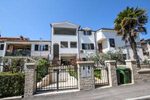 a white house with a gate and a palm tree at Apartman Mila in Poreč