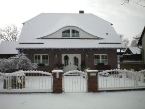 ein Haus mit einem weißen Zaun im Schnee in der Unterkunft Spreewald-Ferienwohnung Reschke in Radensdorf