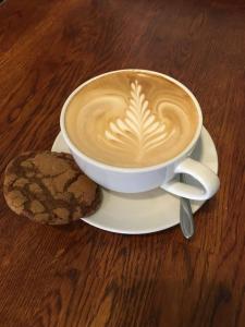 a cup of coffee on a plate with a cookie at The Bath Arms Hotel in Cheddar