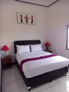 a bedroom with a large bed and two lamps at Sari Room Bed & Breakfast in Nusa Dua