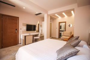 a bedroom with a white bed and a desk at Hotel Kristera in Vlorë