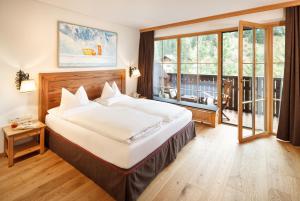 a bedroom with a large bed and a large window at Hotel Lech & Residenz Chesa Rosa in Lech am Arlberg