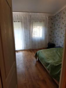 a bedroom with a green bed and a window at Nurmi House in Hajdúszoboszló