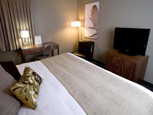ein Hotelzimmer mit einem großen Bett und einem TV in der Unterkunft Heritage Inn Hotel & Convention Centre - Moose Jaw in Moose Jaw