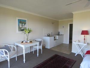 ein Wohnzimmer mit einem Tisch und Stühlen sowie eine Küche in der Unterkunft The Beach House in Port Alfred