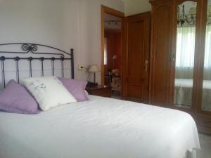 1 dormitorio con 1 cama con almohadas moradas y blancas en Casita Carballo Blanco, en Barral