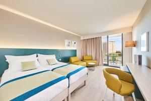 a hotel room with a bed and a desk and chairs at Hotel Sipar Plava Laguna in Umag