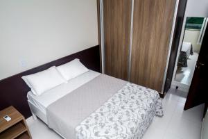a bedroom with a bed and a wooden cabinet at Executivo Flat II in Parauapebas